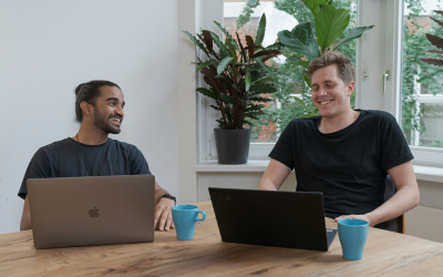 Two men with their laptops engaged in conversation