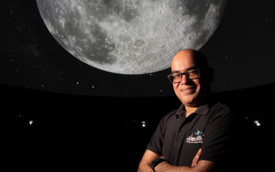 The Open University's Professor Mahesh Anand standing in front of a Moon image - photo by Mark Bolam.