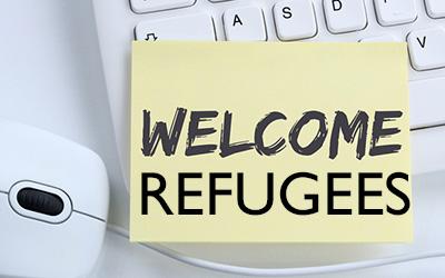 A 'Welcome Refugees' note on a computer keyboard, next to a mouse