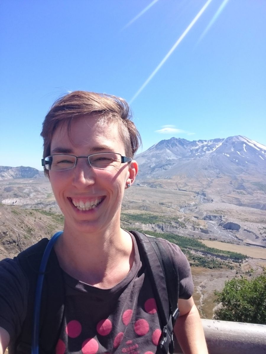 Dr Anne Jay, a volcanologist, standing in front of a volcano.