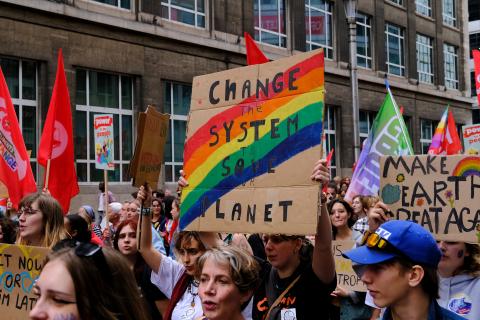 Protesters on a march holding a sign that reads change the system to save the planet