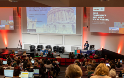 Audience facing a stage with a presentation